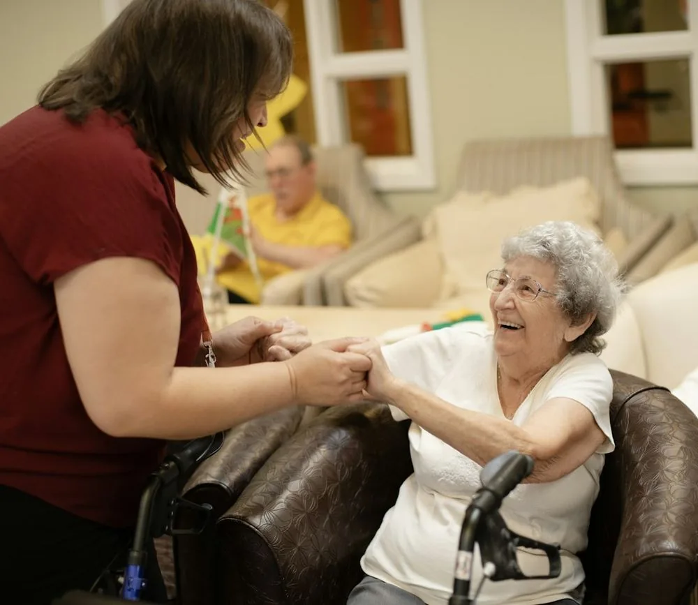 Une soignante aide une patiente âgée à se lever de son fauteuil
