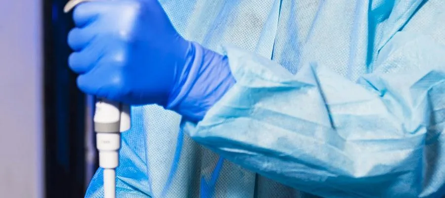 Technicien de laboratoire en blouse et gants bleus manipulant une pipette