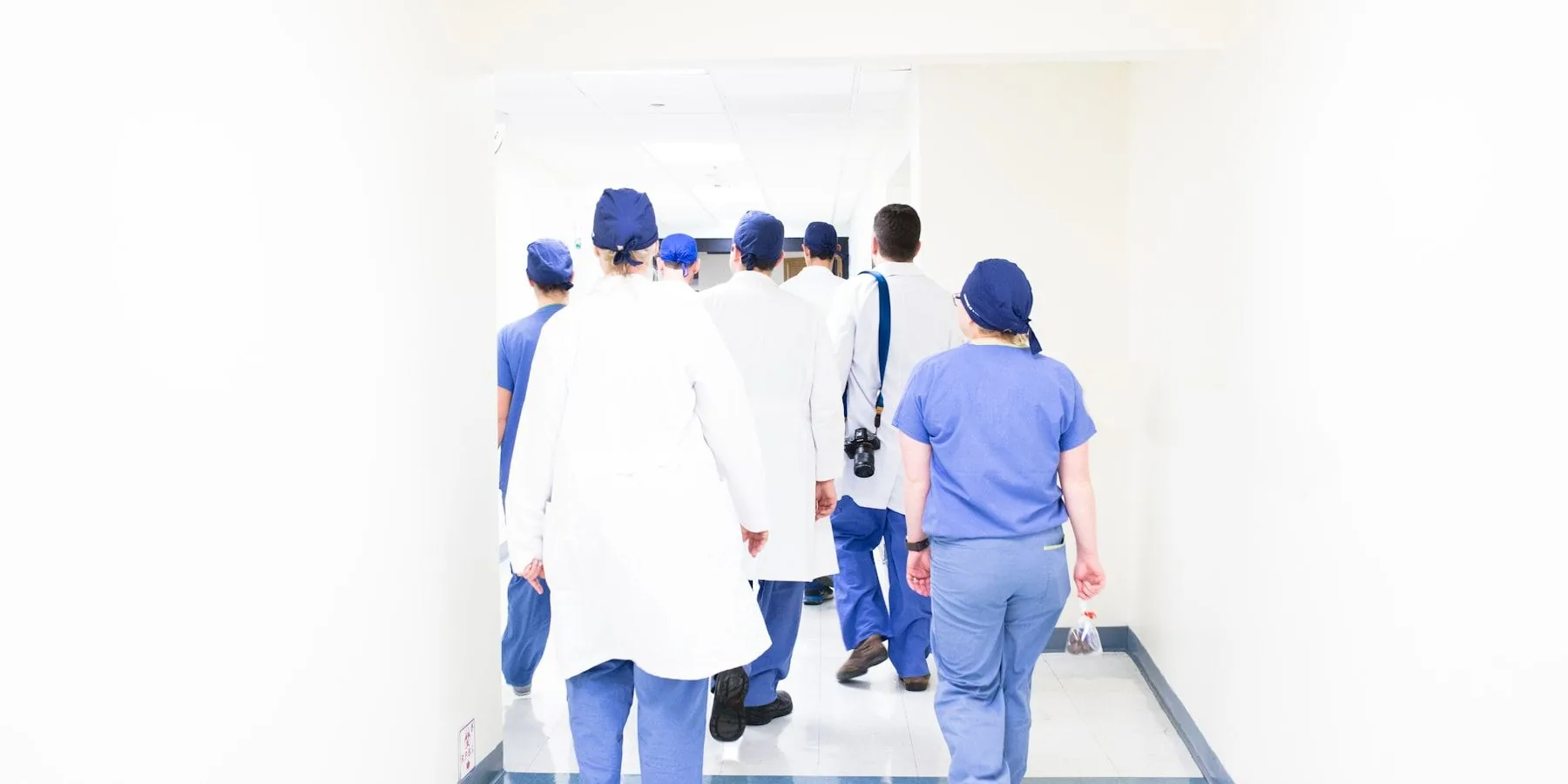 Équipe de soignants en blouse traversant un couloir d’hôpital