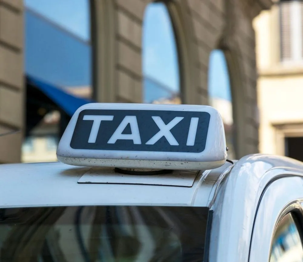 Enseigne lumineuse TAXI sur le toit d’un véhicule, en pleine rue